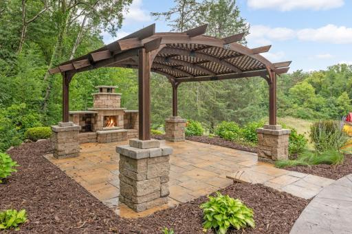 Concrete patio off the pool area features a pergola and outdoor fireplace.