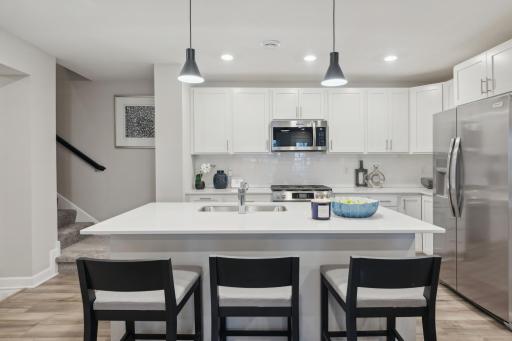 (Photo of a decorated model, actual homes finishes will vary) This spacious kitchen features a large center island, quartz countertops, LVP floors, stainless appliances and more.