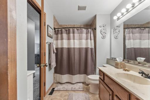 Main level full bathroom. Accessible from the hall and directly from the primary bedroom. Featuring tile floor and tub surround.