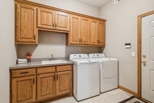 This is the main level laundry room featuring solid oak cabinets, millwork & doors, a large walk-in coat storage closet, Maytag washer & dryer, and utility sink.