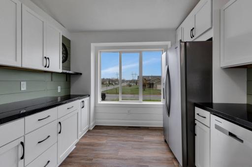 The beautiful kitchen features crisp white cabinets, sleek countertops, coffee bar, shiplap and stainless steel appliances.