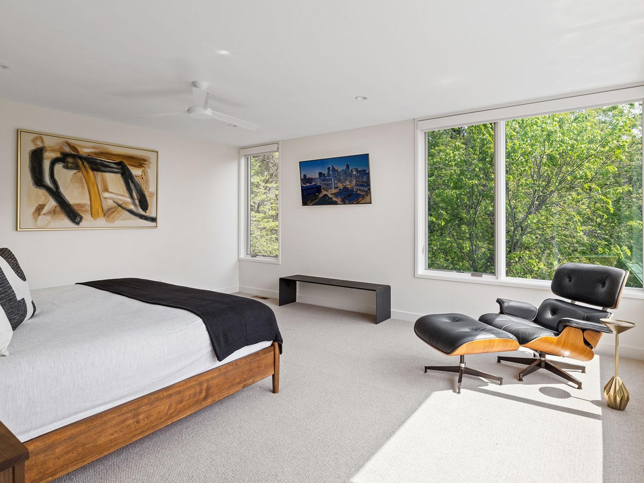 The primary bedroom boasts an abundance of natural light, accentuated by corner windows that offer captivating views of the exquisite backyard.