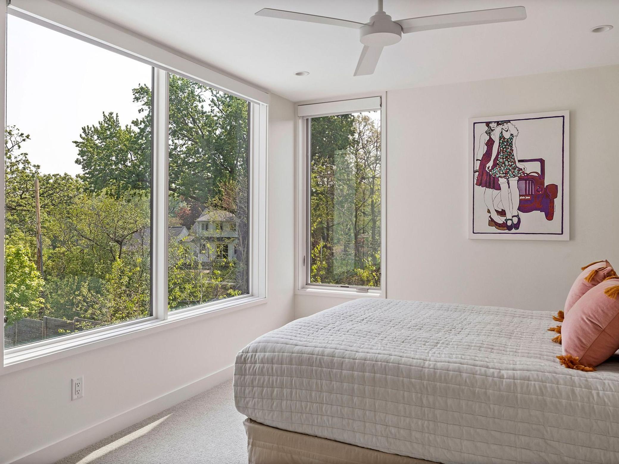 This stunning home features four upper-level bedrooms, including this charming room with corner windows that offer picturesque views.