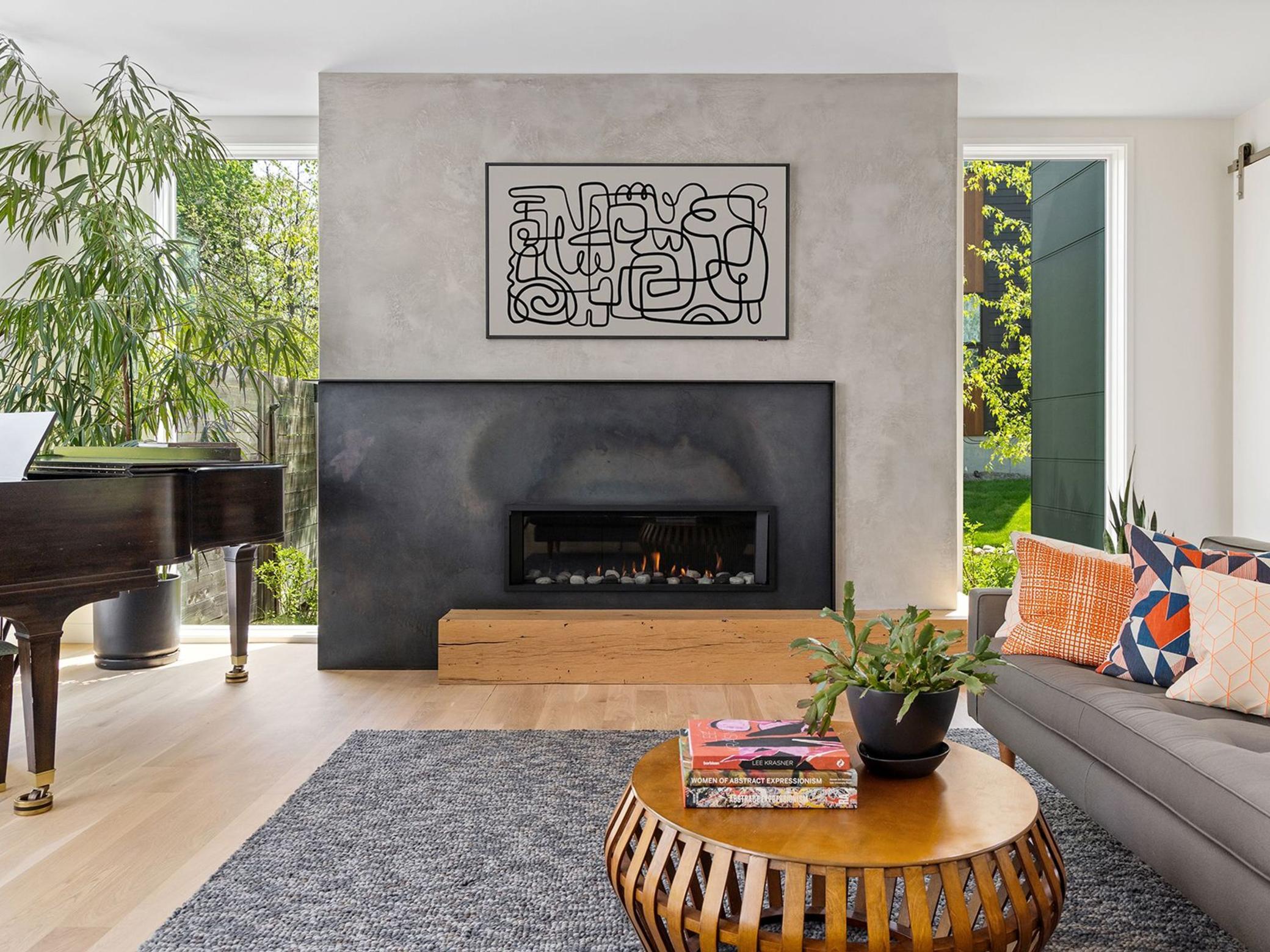 The kitchen and dining areas transition effortlessly into the living room. The custom concrete and steel gas fireplace anchor the space, providing inviting symmetry.