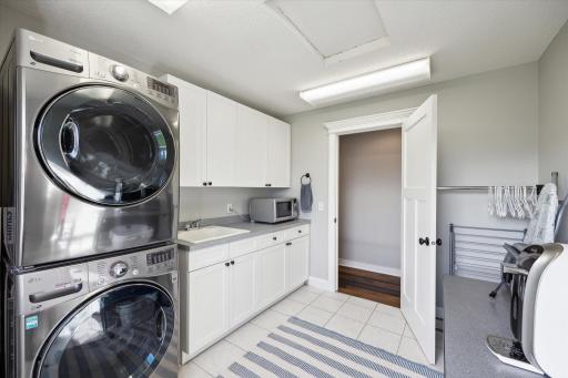 Spacious laundry room with full size machines, cabinetry and utility sink.