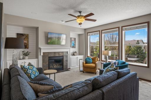 Bask in the natural light of the sun-filled living room, featuring a cozy gas-burning fireplace framed by dual built-in cabinetry and a stylish shiplap surround, creating a warm and inviting ambiance for relaxation or entertaining.