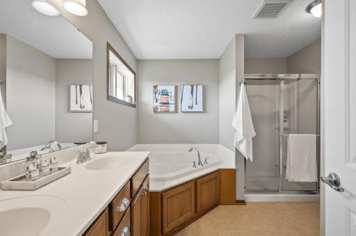 Pamper yourself in the spa-like private bathroom featuring tile floors, dual sinks, a corner soaking tub, and a walk-in shower stall, providing the ultimate in luxury and comfort.