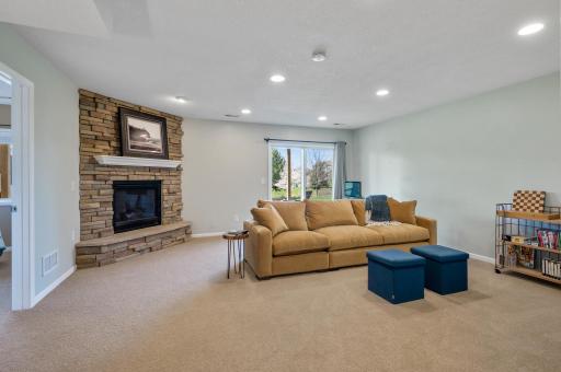 The lower level walk-out family room beckons with an additional cozy gas-burning fireplace adorned with floor-to-ceiling stacked stone surround.