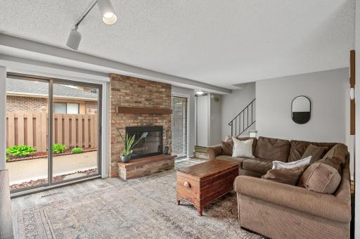 Inviting living room with newer sliding door with access to the private patio. Floor to ceiling brick wood burning fireplace & newer luxury vinyl plank flooring that is consistent throughout the main floor gathering spaces.