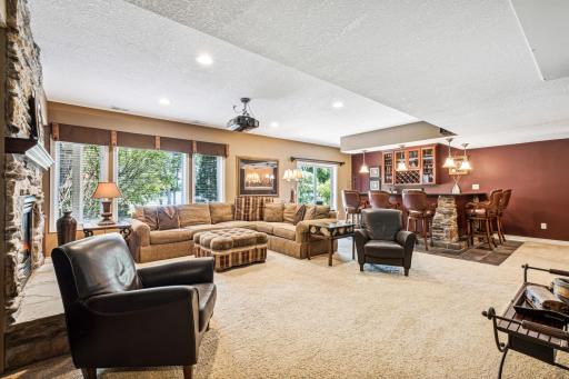 A Prairie Pub style wet bar combines rustic wood and stone with cozy pub ambiance. It features a spacious counter, open shelving, a mini-fridge, a sink, and comfortable stools.