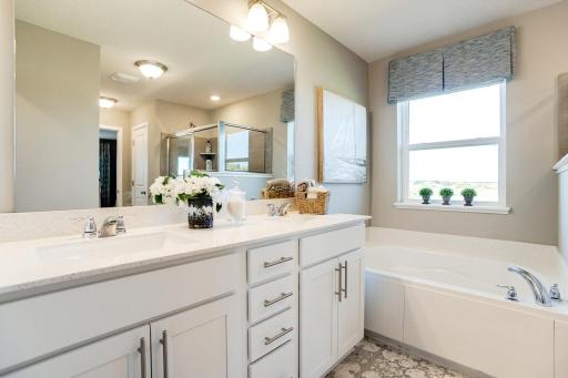 Inside the primary suite bathroom you will find an over-sized shower, plus a soaking tub, double vanity and private water-closet. Photo of model home. Selections will differ.