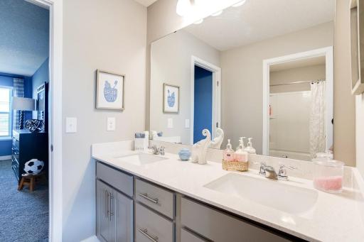 The secondary hall bath is a jack-and-almost-jill -- connected to a bedroom on one side and exiting to a hall across from another secondary bedroom. Photo of model home. Selections will differ.