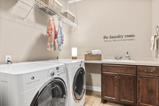 Main floor laundry with durable tile floor and convenient sink, countertop, and cabinets.