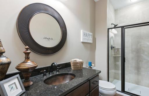 Main floor 3/4 bathroom features wood floors and step in shower with tile surround.