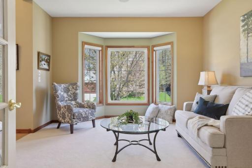Front living room boasts neutral decor, bay window with custom window treatments and French Doors.