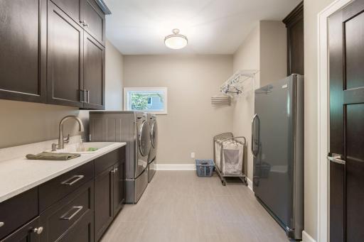 Separate Laundry room has ample counter space and full sink with broom closet, refrigerator, and built in cabinetry for storage.