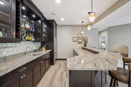 Raised granite island with seating at the wet bar. Custom cabinetry.