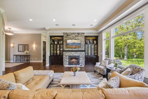 Beautiful Stone gas fireplace with built-in cabinetry and lighted shelving. Ceilings are 11 foot. Wall of windows views the private back yard.