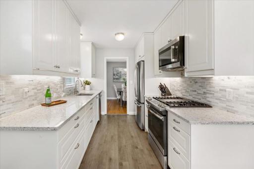 Gorgeous kitchen has quartz countertops, tile backsplash & stainless steel appliances.