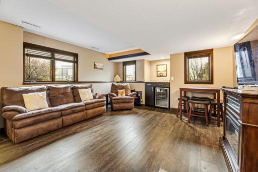 Stunning lower level family room with low-maintenance flooring, a wine cooler, exquisite wood accents, and striking contrast.