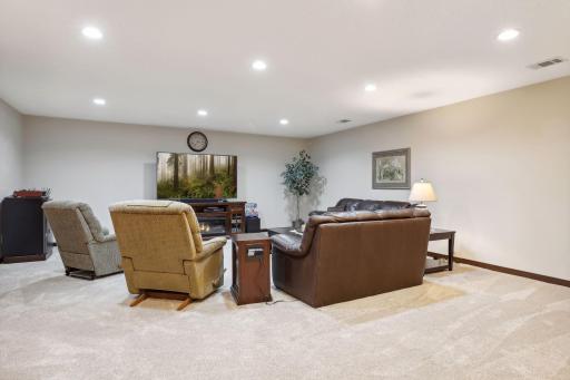 Large lower level family room with tall ceilings and high end carpet.