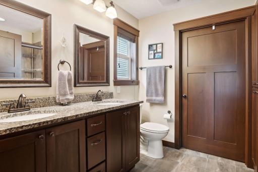 Primary private bath with granite counters on the double sink vanity, and tiled floors and shower.