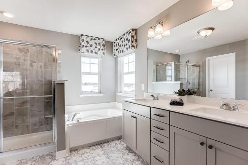 A peak inside the bathroom off the Primary Suite. Notice the extra high cabinets and double-bowl Quartz covered vanity with loads of storage! (Photo of model, colors may vary)