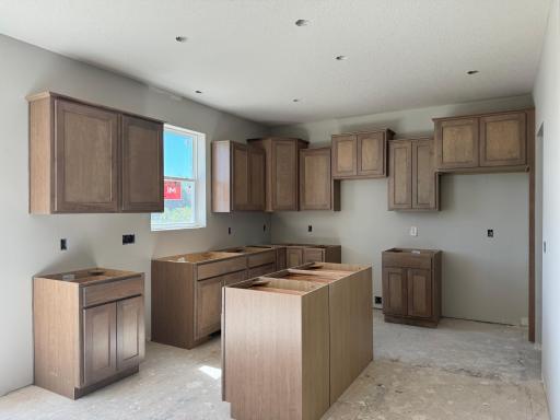 This kitchen features stained maple cabinetry paired with white quartz countertops and tile backsplash, beautifully accented by bronze pulls and faucet. Home will be fully finished with stainless GE appliances.