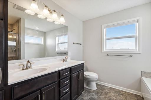 Experience opulent convenience in the en suite bath, boasting double sinks, a separate soaking tub, and a luxurious shower, blending functionality with indulgence for a rejuvenating escape