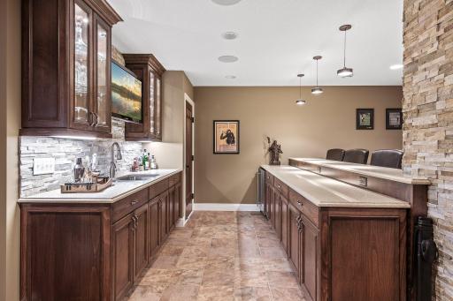 Featuring a full bar with a wine cellar, double sink, refrigerator, custom beech cabinetry, and granite countertops.