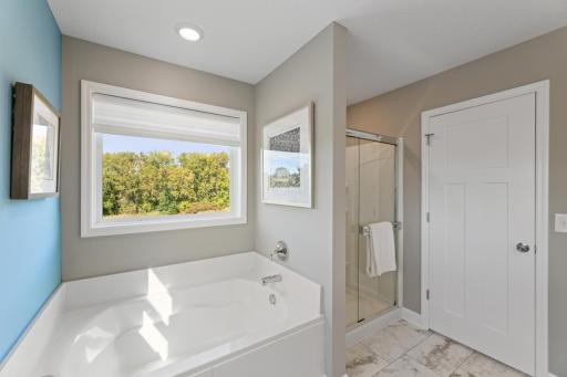 (*Photo of decorated model, actual homes finishes and colors will vary) An extension of the owner's suite, this private and spacious bath contains a double-vanity, a separate shower, and a soaking tub.