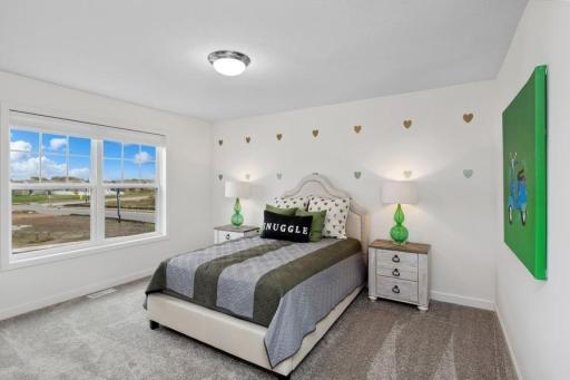 (Photo of decorated model, actual home's finishes will vary) One of three generously sized upper level secondary bedrooms with spacious closets.