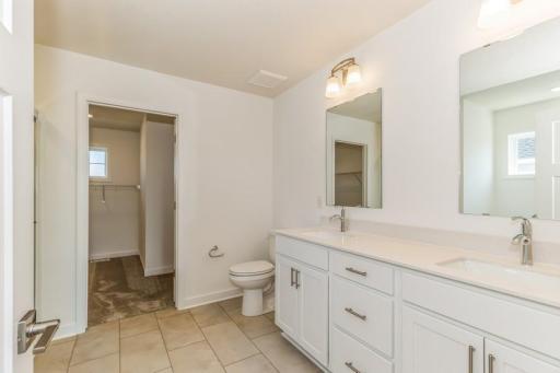 Photo is of the actual home. An extension of the primary bedroom, this private and spacious bath contains a double-vanity, a soaking tub and a separate shower.