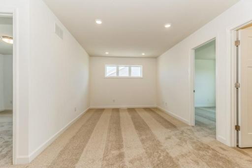Photo is of the actual home. Located on the upper level, this perfectly sized living space has enough room for a desk, television and seating for all.