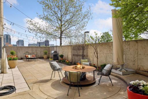 A private patio hidden behind walls boasts a fire pit, a gas grill, and gardens.