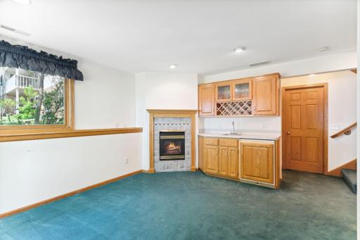 Lower level Amusement Room features a wet bar with mini-fridge & gas fireplace