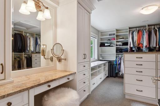Walk-in closet with dressing table, built-ins and even additional storage behind the full length mirror