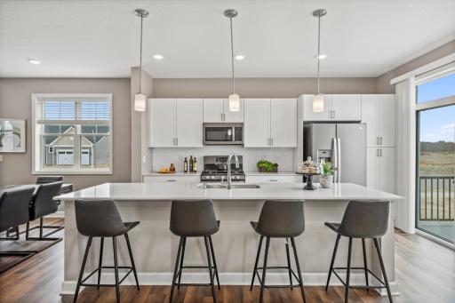 (Photo of a decorated model, actual homes finishes will vary) Enjoy plenty of seating at the kitchen island and dining area adjacent to the kitchen. Perfect for entertaining or having a family meal together.