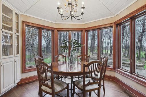 Wrapped in windows with private views, the breakfast nook features a vaulted ceiling and built-in hutch