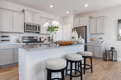 (Photos of model, finishes may vary) Features include stainless appliances, a spacious walk-in pantry, granite counters and a ceramic backsplash that ties the kitchen together.