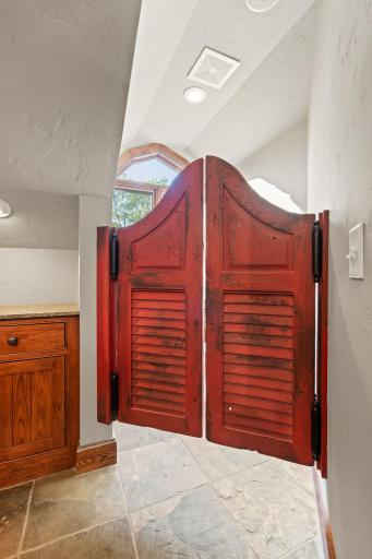 Seperate room for toilet and offers a large storage cabinet - reclaimed saloon doors offer privacy