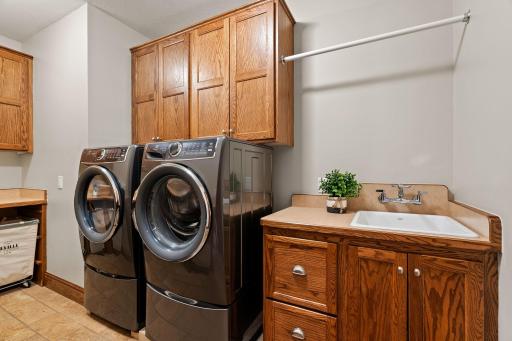 Laundry Room features an abundance of oak cabinetry that offers storage and large folding counter with drop in sink and wall mounted faucet