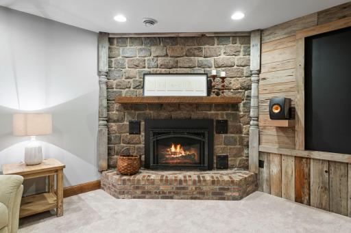 Corner gas fireplace w/ stone surround and brick covered raised hearth