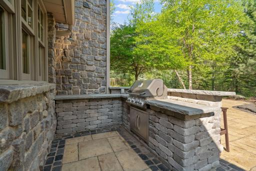 Built-in BBQ station offers a gas grill with generously sized paver surround, concrete top and raised counter to accommodate stools