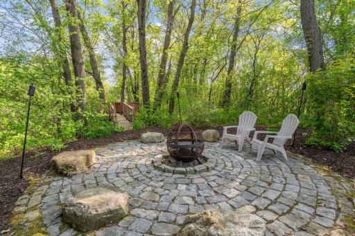Round paver patio situated perfectly in the natural wooded area and has a built-in fire ring