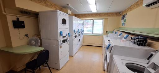 The laundry room has 8 washer and 8 dryers, a small sitting area, and a wash tub.