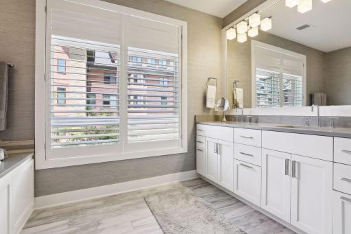 Heated floors, dual sinks, custom plantation shutters, and cabinet space for bath essentials