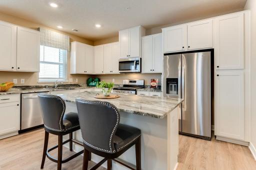 This kitchen is sure to impress with vinyl plank flooring, white cabinets, and granite countertops. Photo of model home, colors and options may vary.