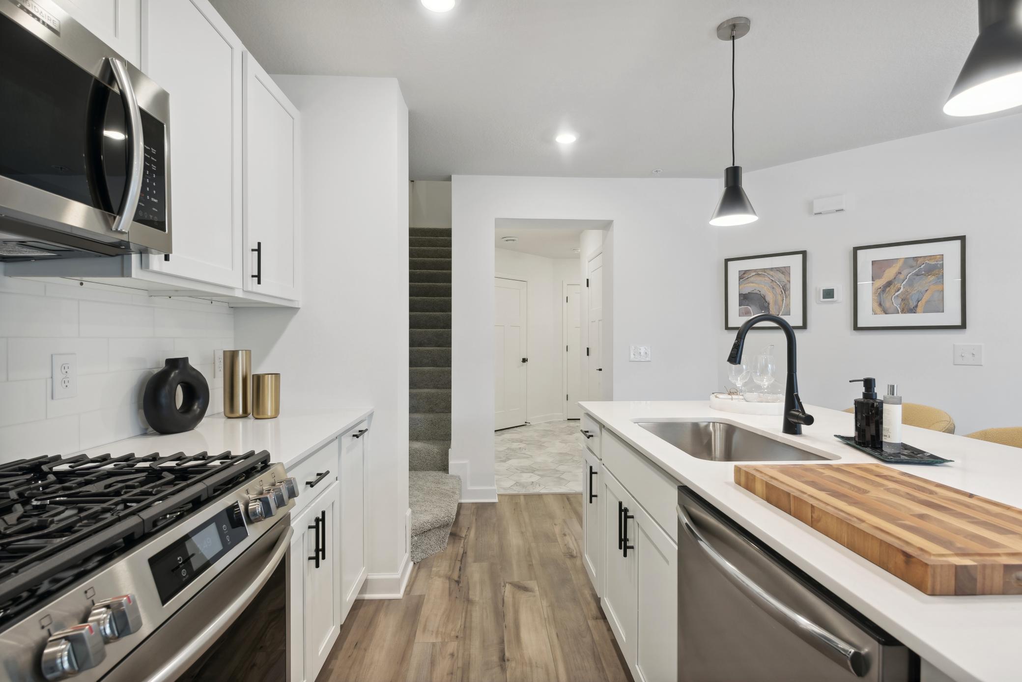 (*Photo of decorated model, actual homes colors and finishes will vary) The kitchen is home to a large center island complete with quartz countertops, stainless appliances, and a luxurious gas cooktop.