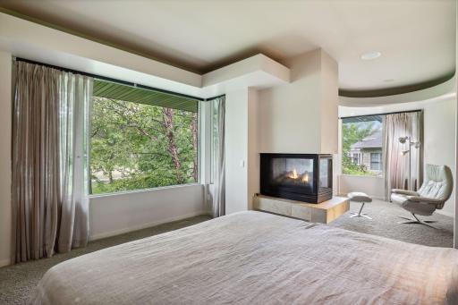 Three sided gas fireplace located between bedroom and sitting area